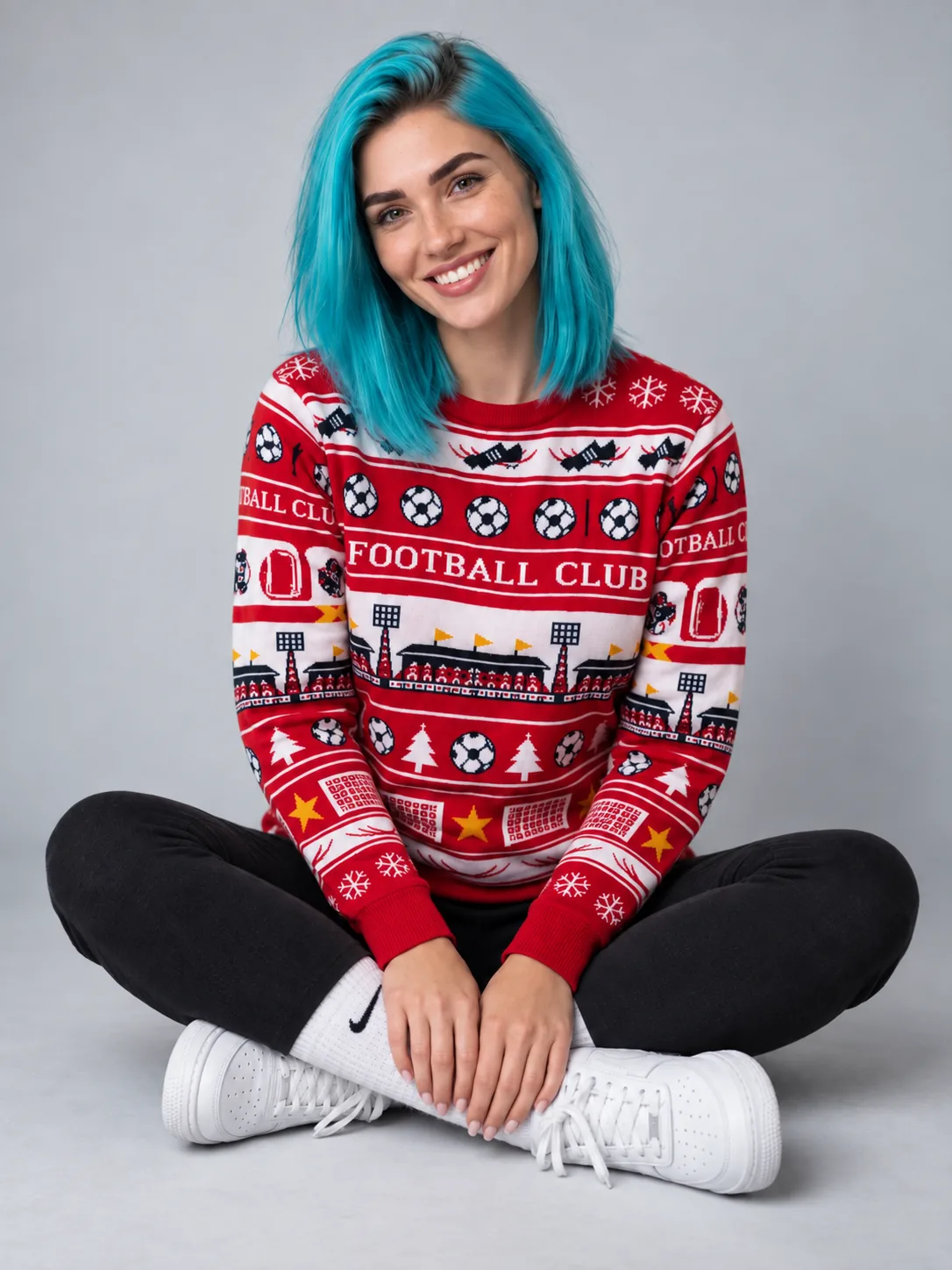 Sian smiling in a custom football club Christmas jumper, seated cross-legged.